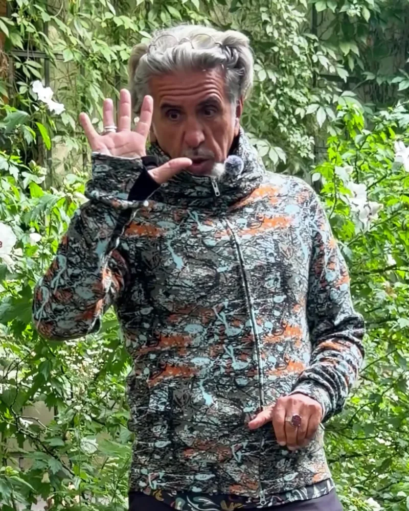 Hamid in der geschlossenen Jacke Nilo, der Kragen steht hoch, er zeigt auf die langen Stulpen an den Ärmeln
