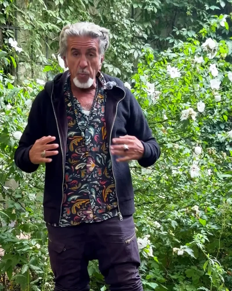 Hamid in der offenen schwarzen Jacke Nilo aus Merinowolle über einem bunten Hemd