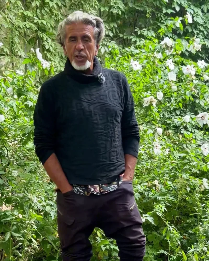 Hamid steht im Garten im Pullover Younes