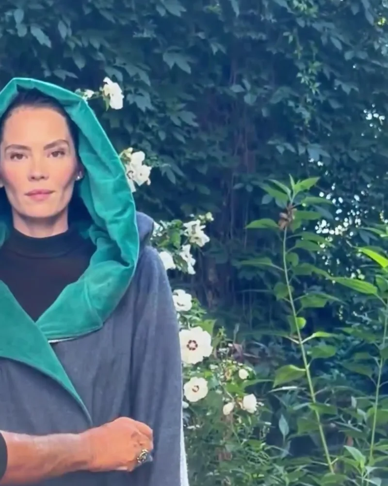 Elisabeth trägt die Kapuze des Mantels Mara, das Gesicht ist von Petrol eingerahmt