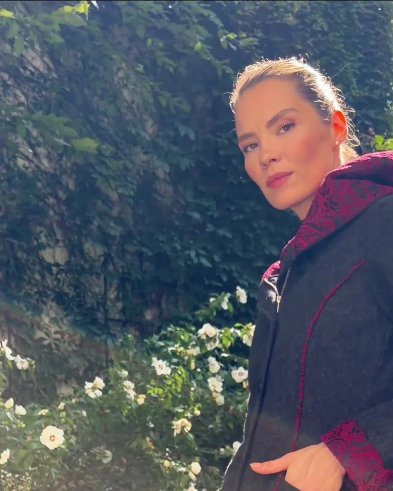 Elisabeth geht im Mantel Mimi durch den Garten